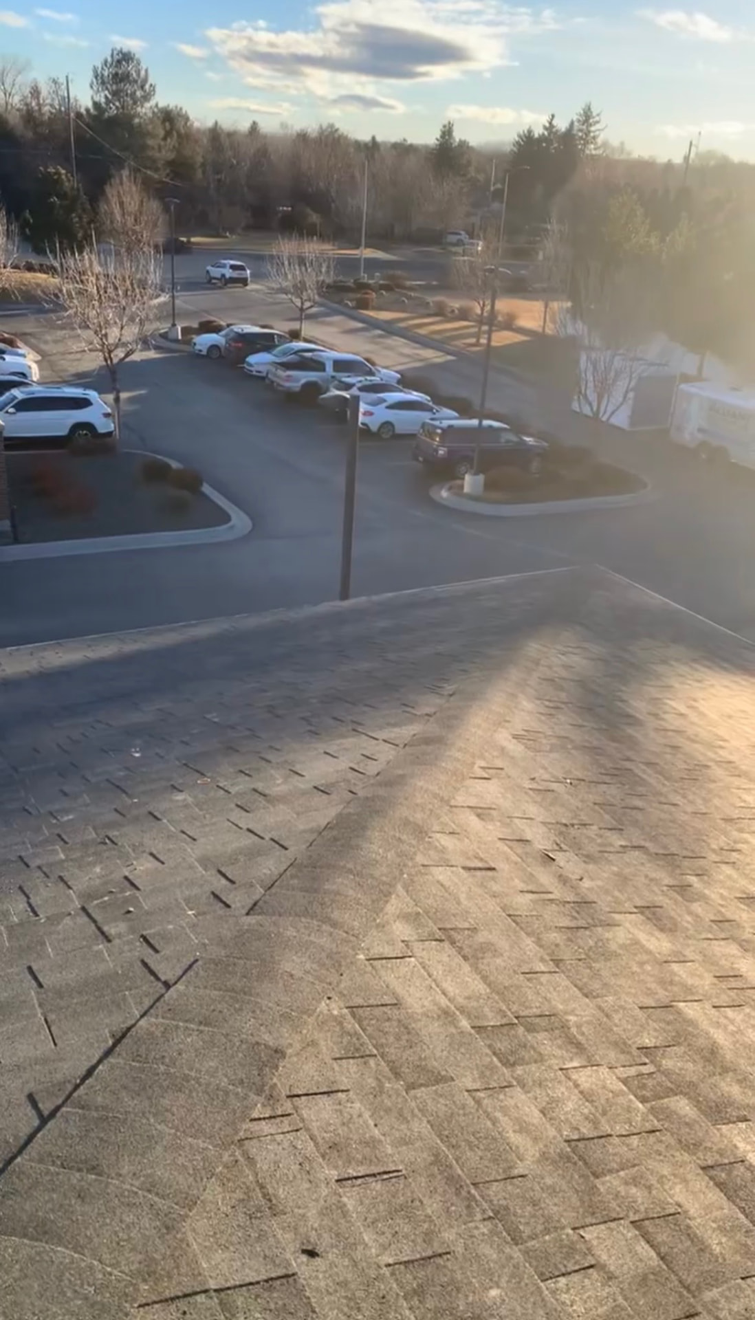 Commercial shingle roof overlooking a parking lot at sunrise